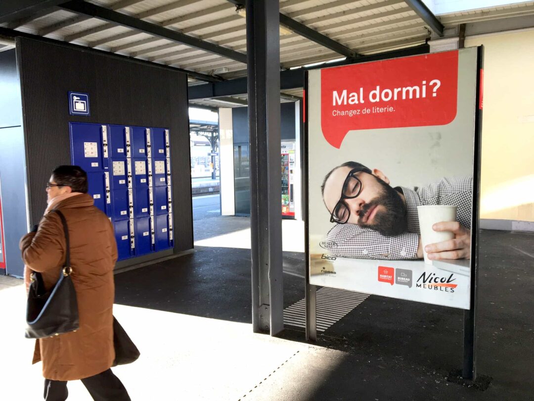 Photo d'une affiche de pub pour Nicol meubles à la gare avec écrit: "bien dormi?".