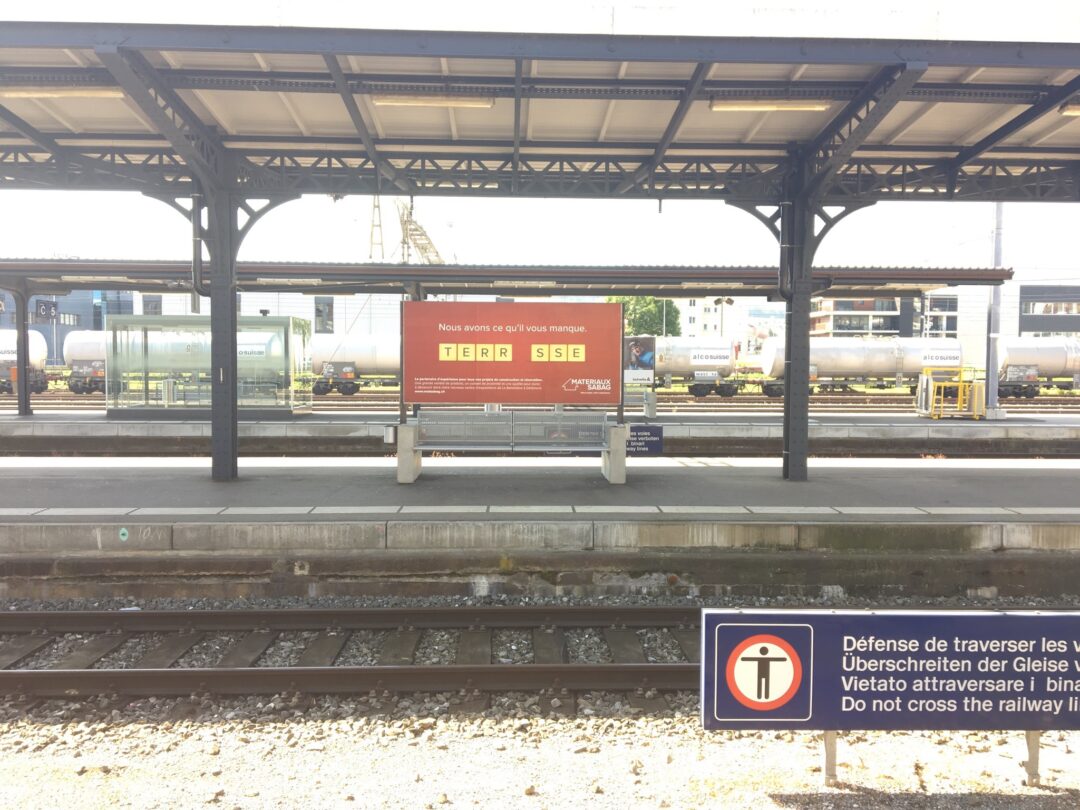 Pancarte à côté des voix de chemin de fer avec écrit "Nous avons ce qu'il vous faut" ainsi que le mot "terrasse".