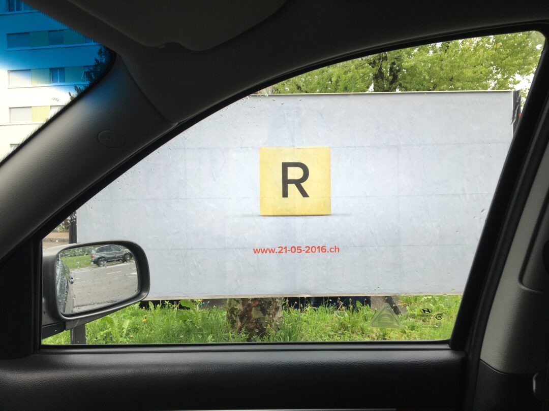 Pancarte avec la lettre "r" dans la rue vu depuis une voiture.